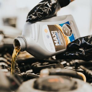 Close-up of a mechanic pouring engine oil into a car engine, highlighting maintenance work.